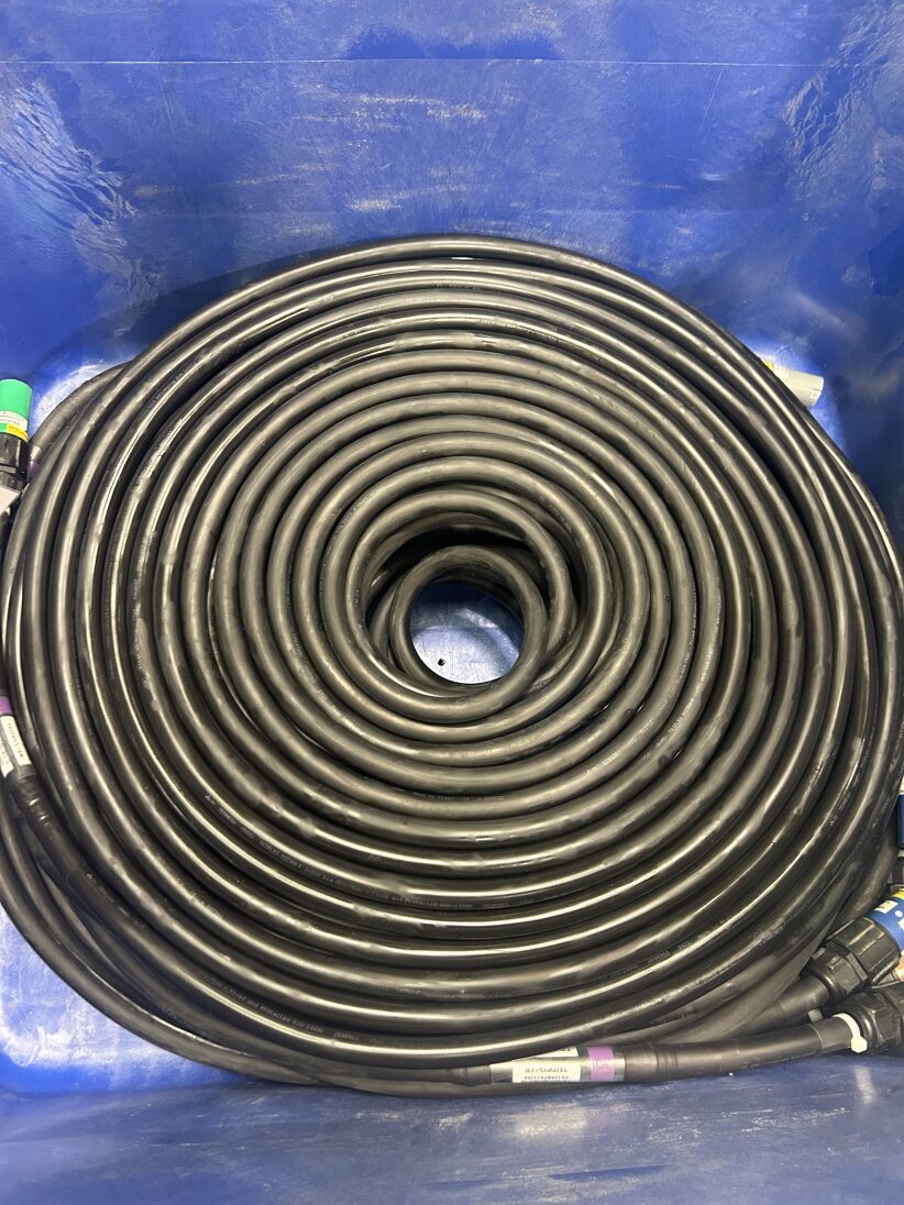 A large black cable coiled neatly in a spiral inside a blue container, with connectors visible at the cable ends.
